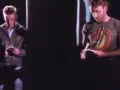 Dwóch mężczyzn czyta. Jeden w kurtce, drugi w koszulce z napisem. Atmosfera jak z "Blue Monday" New Order.
