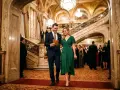 Elegancka para wchodzi na galowy wieczór. Czy to filharmonia? Wspaniałe wnętrze, schody i kryształowe żyrandole sugerują uroczystość.