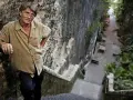 Mike Oldfield, znany muzyk, stoi na kamiennych schodach. Może to miejsce, gdzie mieszkał z żoną.