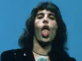 Freddie Mercury z wyciągniętym językiem, śpiewający do mikrofonu. W jego oczach widać pragnienie, by **break free**.