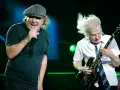 Brian Johnson śpiewa, Angus Young gra na gitarze podczas jednego z legendarnych **AC/DC koncertów**.