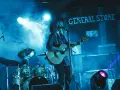 Artystka w kapeluszu gra na gitarze, wykonując najpopularniejsze piosenki country. W tle perkusja i napis "GENERAL STORE".
