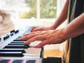 Dłonie grające na keyboardzie. To instrument muzyczny, który pozwala tworzyć melodie.
