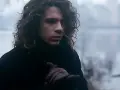 Mężczyzna z kręconymi włosami w czarnym płaszczu, trzymający się za rękę, jakby chciał powiedzieć "never tear us apart".