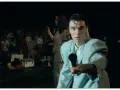 David Byrne z The Cult - Be Free, śpiewa do mikrofonu na tle tłumu.