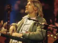 Kurt Cobain z papierosem w dłoni, grający na gitarze. Jego muzyka to część 100 najlepszych piosenek wszechczasów.