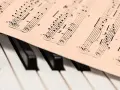 Partytura z nutami na klawiaturze pianina, gotowa do zagrania najsłynniejsze utwory jazzowe.