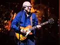 Mark Knopfler na scenie, grając na gitarze Gibson Les Paul. Jego charakterystyczne utwory brzmią w tej chwili na żywo.