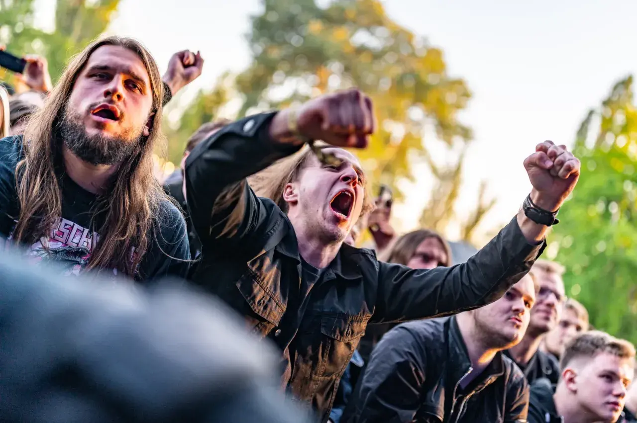 Młodzi ludzie z podniesionymi pięściami, krzyczący na koncercie. Czy to skinhead? Niekoniecznie, to po prostu fani muzyki.