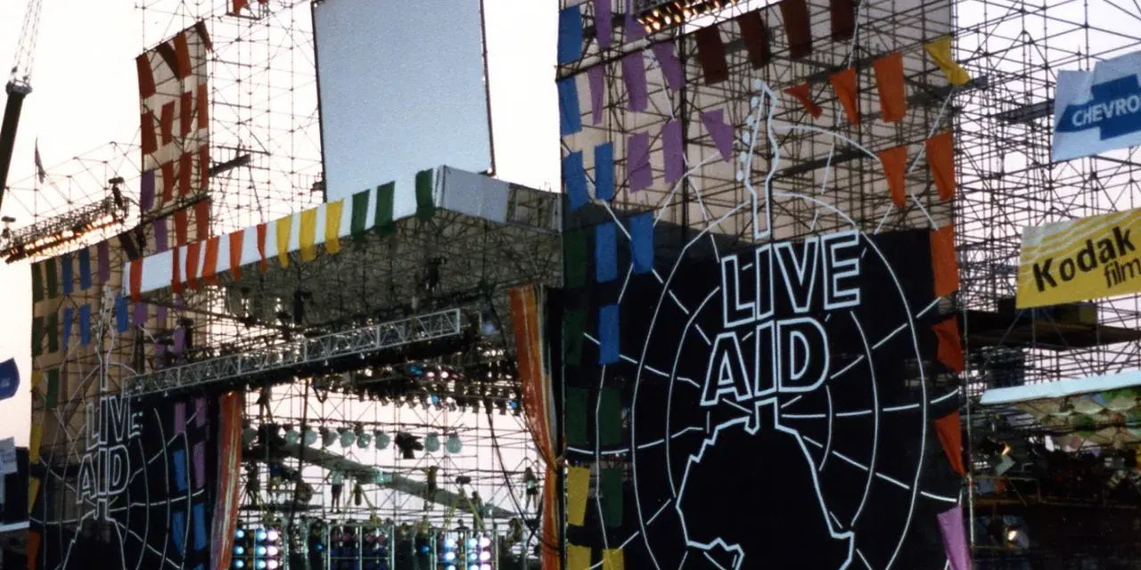 Scena Live Aid w Polsce, ozdobiona kolorowymi flagami i wielkim logo.