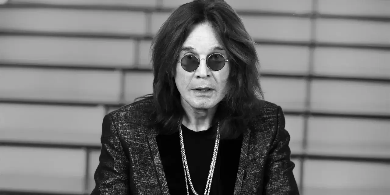 Ozzy Osbourne w okularach i błyszczącej marynarce, z naszyjnikami. Plotki o tym, że Ozzy Osbourne nie żyje, są fałszywe.