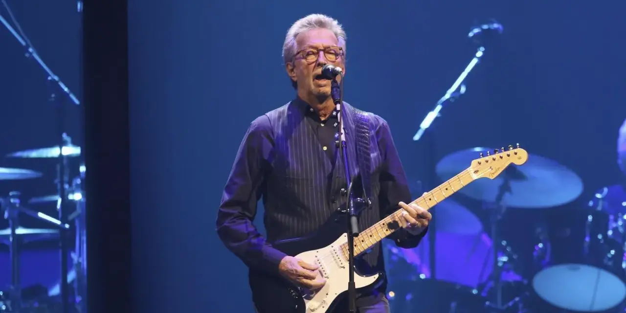 Eric Clapton gra na gitarze, wykonując swoje legendarne utwory.