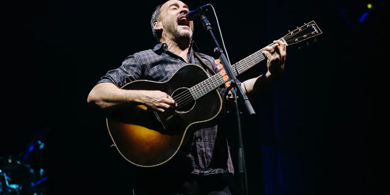 Dave Matthews z DMB śpiewa i gra na gitarze akustycznej na scenie.