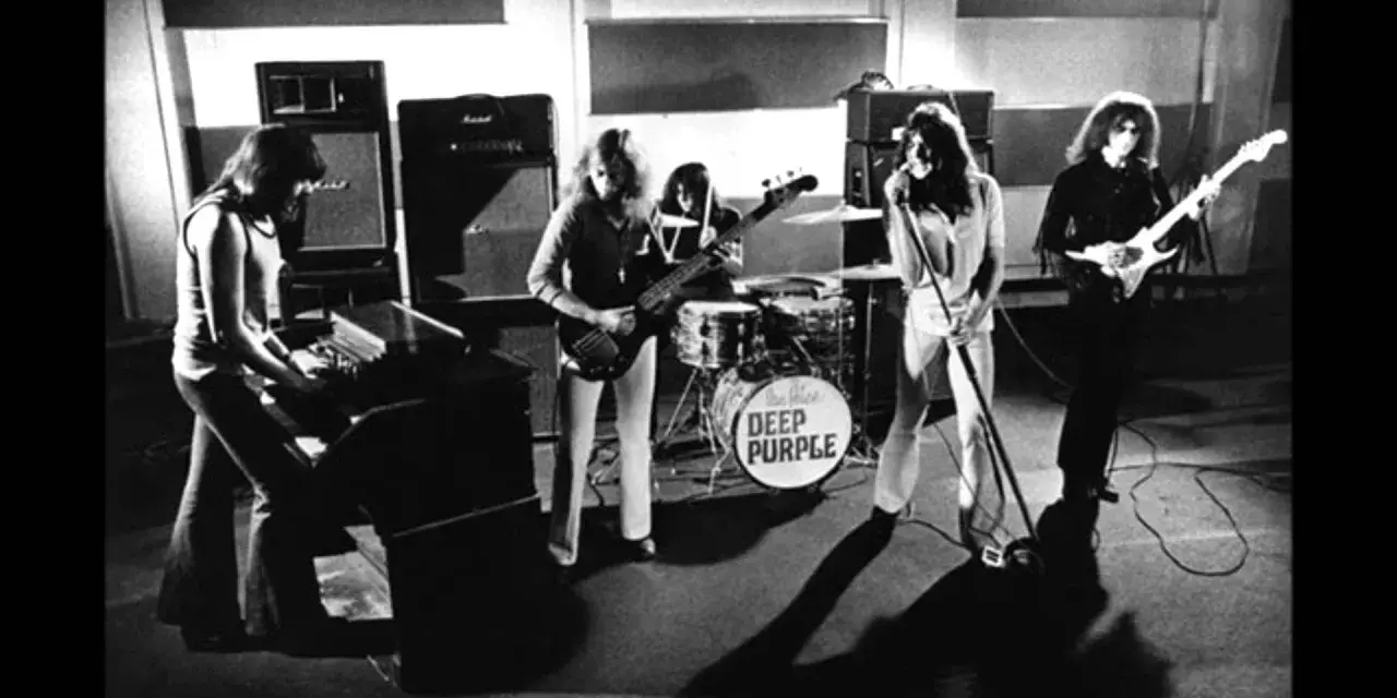 Zespół Deep Purple w akcji. Muzycy grają na instrumentach, w tle perkusja z logo zespołu.