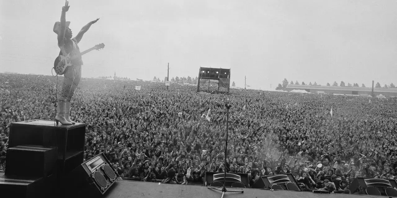 Ogromny tłum na koncercie Metallica Moskwa 1991. Wokalista na scenie, ręce w górze, wita fanów.