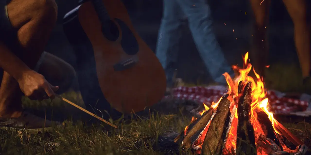 Przy ognisku, z gitarą w tle, rozbrzmiewają piosenki turystyczne i harcerskie.