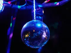 Lśniąca kula dyskotekowa, wisząca na łańcuchu, odbija kolorowe światła. To właśnie takie klimaty kojarzą się z pytaniem: silent disco co to?