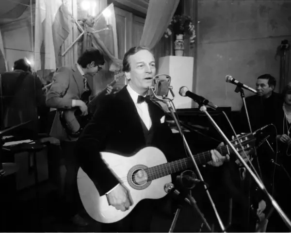 Zbigniew Kurtycz z gitarą i zespołem wykonuje swoje utwory. Wokalista w czarnym aksamitnym fraku śpiewa do mikrofonu.