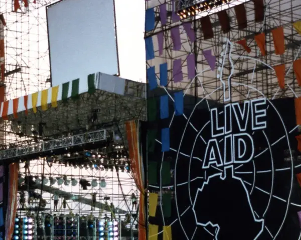 Scena Live Aid w Polsce, ozdobiona kolorowymi flagami i wielkim logo.