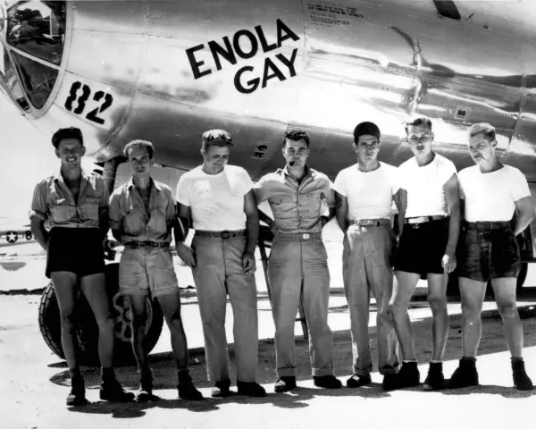 Siedmiu mężczyzn w mundurach przed samolotem Enola Gay. "Enola Gay co to znaczy?" - nazwa samolotu, który zrzucił bombę atomową na Hiroszimę.
