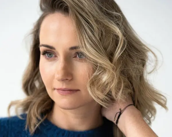 Zuzanna Irena Grabowska z burzą blond włosów i niebieskimi oczami, w granatowym swetrze.