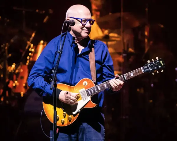 Mark Knopfler na scenie, grając na gitarze Gibson Les Paul. Jego charakterystyczne utwory brzmią w tej chwili na żywo.