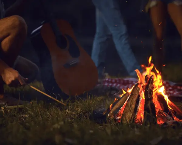 Przy ognisku, z gitarą w tle, rozbrzmiewają piosenki turystyczne i harcerskie.