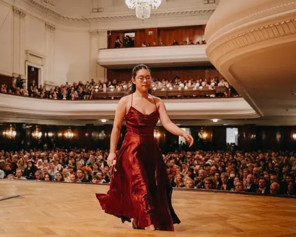 Młoda pianistka w czerwonej sukni wchodzi na scenę, by wykonać nokturn. Publiczność w teatrze czeka na występ.