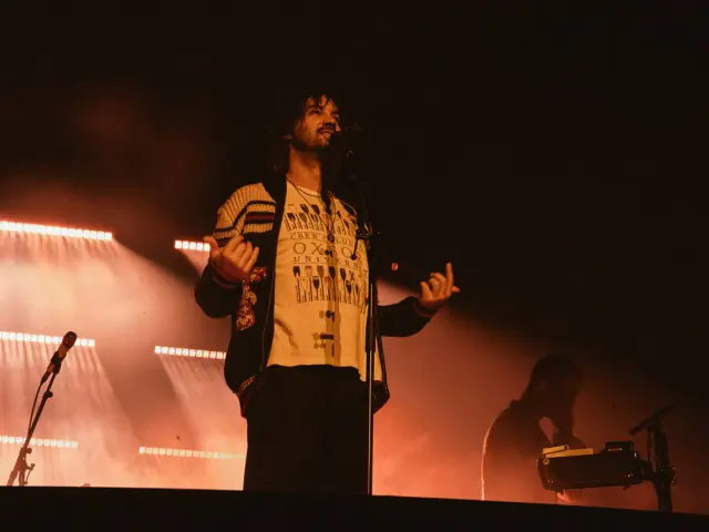 Kevin Parker z Tame Impala na koncercie w Gliwicach, w otoczeniu pomarańczowych świateł scenicznych.