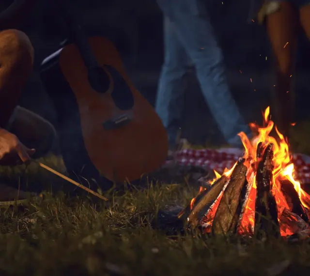 Przy ognisku, z gitarą w tle, rozbrzmiewają piosenki turystyczne i harcerskie.