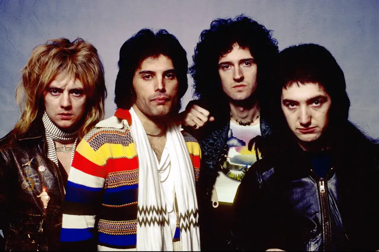 Czterech członków zespołu Queen, w tym Freddie Mercury, Brian May, Roger Taylor i John Deacon, pozuje do zdjęcia. Ta ikoniczna queen w Polsce z pewnością zachwyciłaby fanów.
