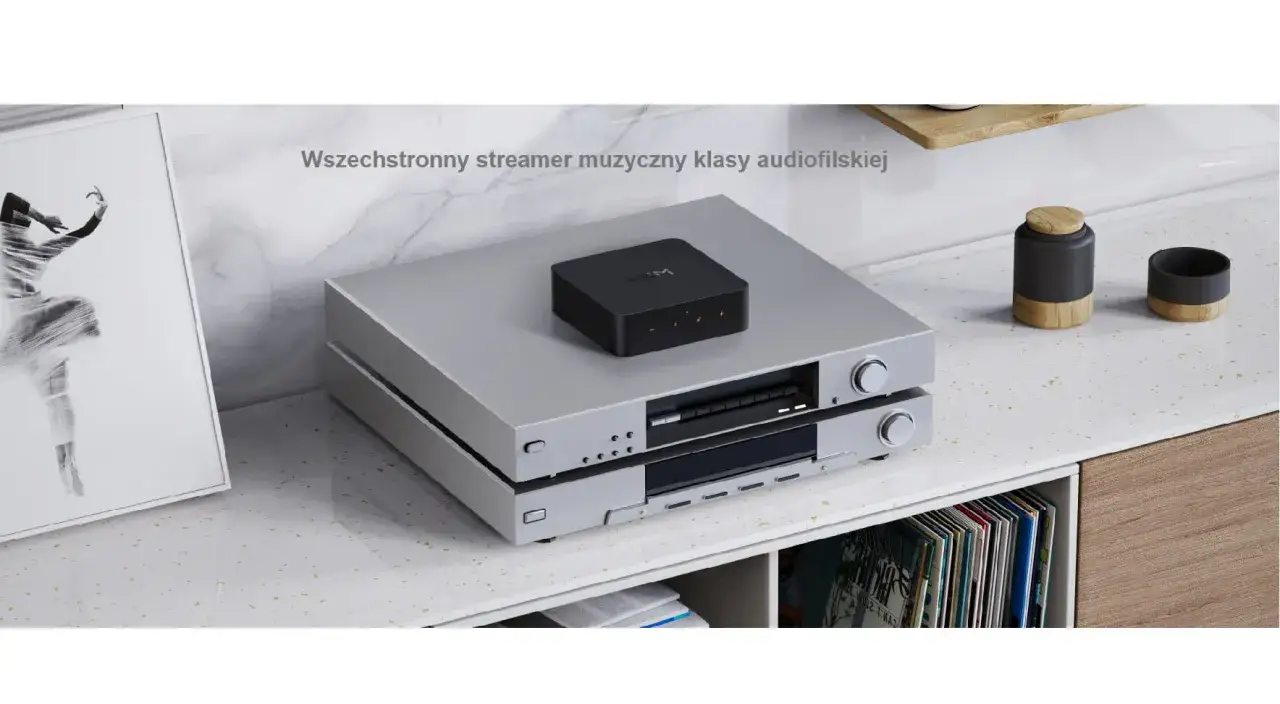 Elegancki, czarny streamer muzyczny klasy audiofilskiej, umieszczony na srebrnym sprzęcie audio.