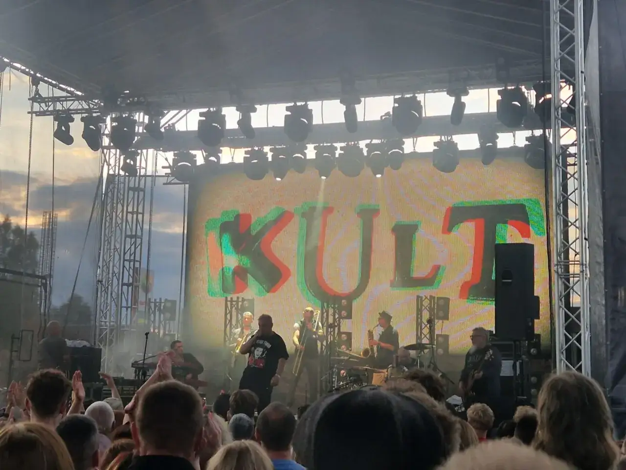 Koncert zespołu Kult. Kazik Staszewski na scenie, tłum widzów. W tle wielki napis KULT.