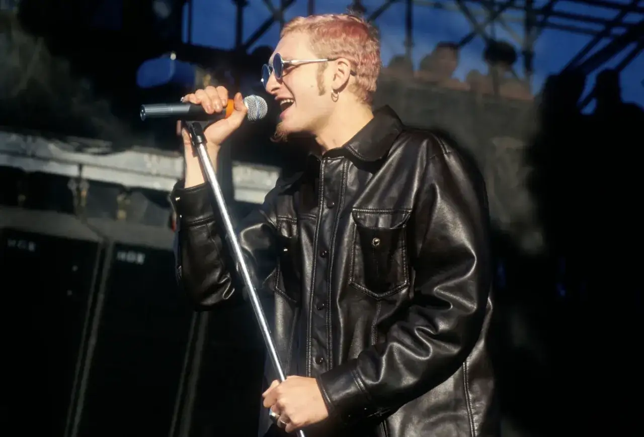 Layne Staley w skórzanej kurtce, śpiewający do mikrofonu. Jego śmierć wciąż porusza fanów.