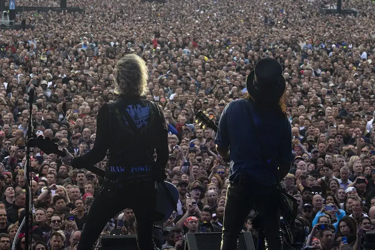 Dwóch muzyków Guns N' Roses na scenie przed morzem fanów. Niezapomniane koncerty, które na zawsze pozostają w pamięci.
