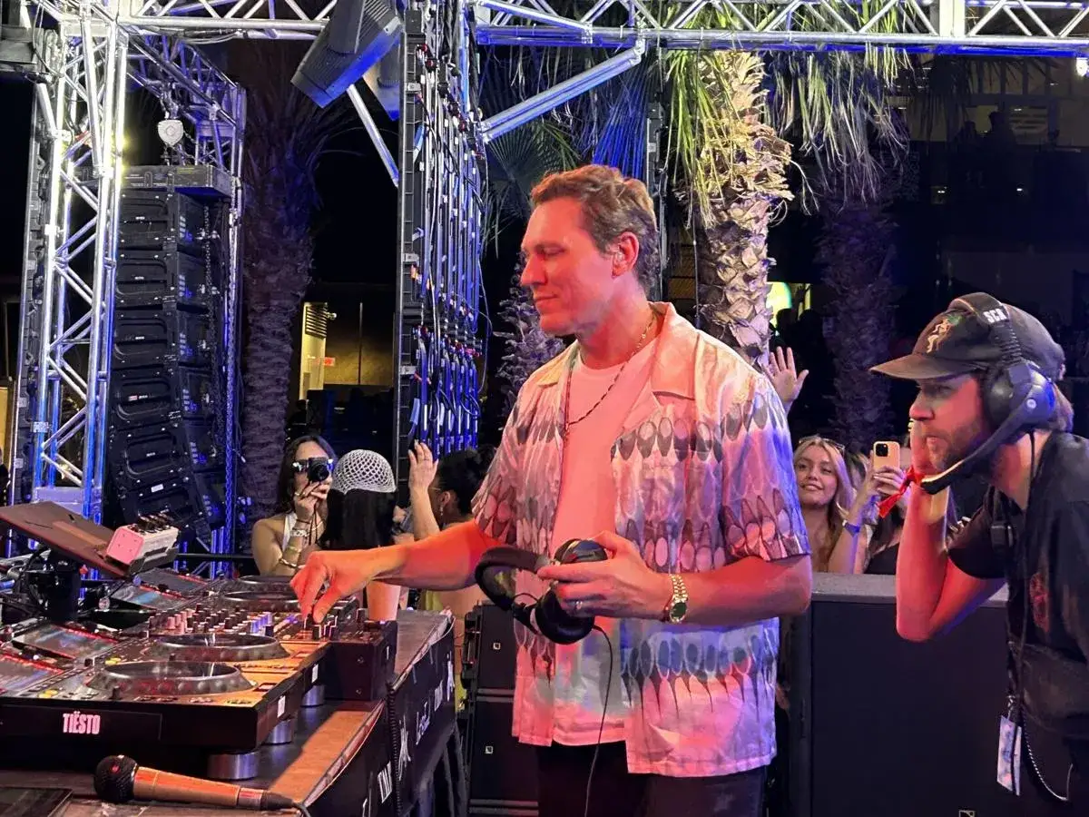 DJ Tiesto gra koncert w Polsce. W tle palmy i tłum bawiących się ludzi.