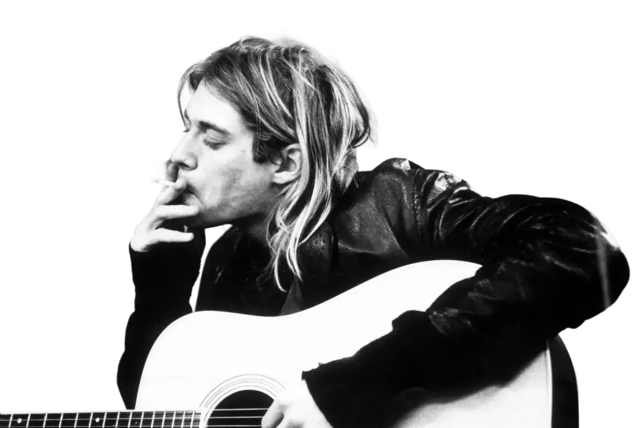 Kurt Cobain z papierosem w dłoni, grający na gitarze akustycznej.