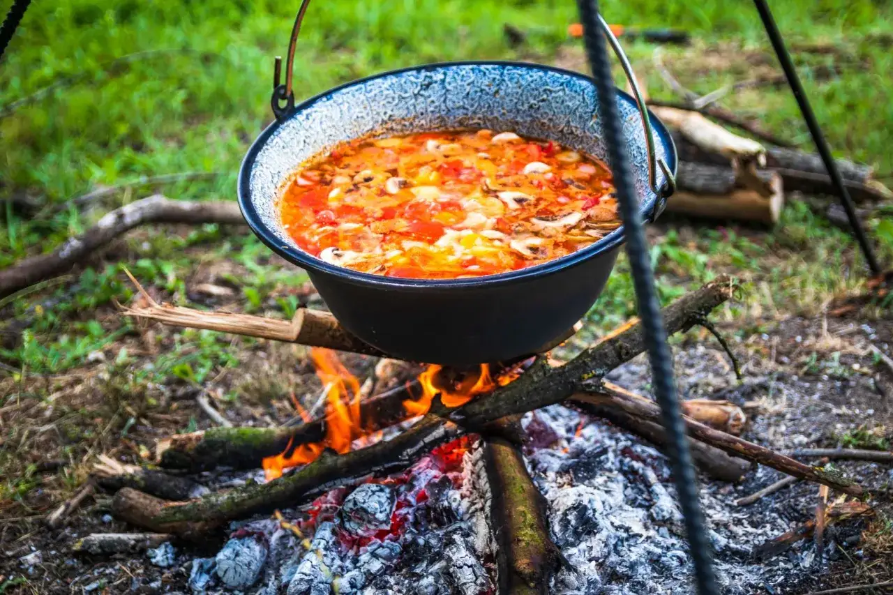 Gulasz z kociołka żeliwnego na ognisku, pachnący i sycący, gotuje się powoli na drewnianym ogniu.