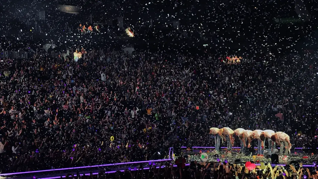 Tłum fanów na koncercie, sypiący się konfetti. Grupa artystów kłania się na scenie. Fani czekają na BTS tour 2026.
