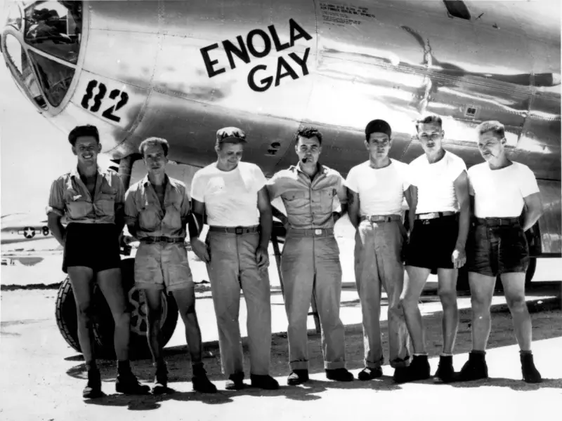 Siedmiu mężczyzn w mundurach przed samolotem Enola Gay. "Enola Gay co to znaczy?" - nazwa samolotu, który zrzucił bombę atomową na Hiroszimę.
