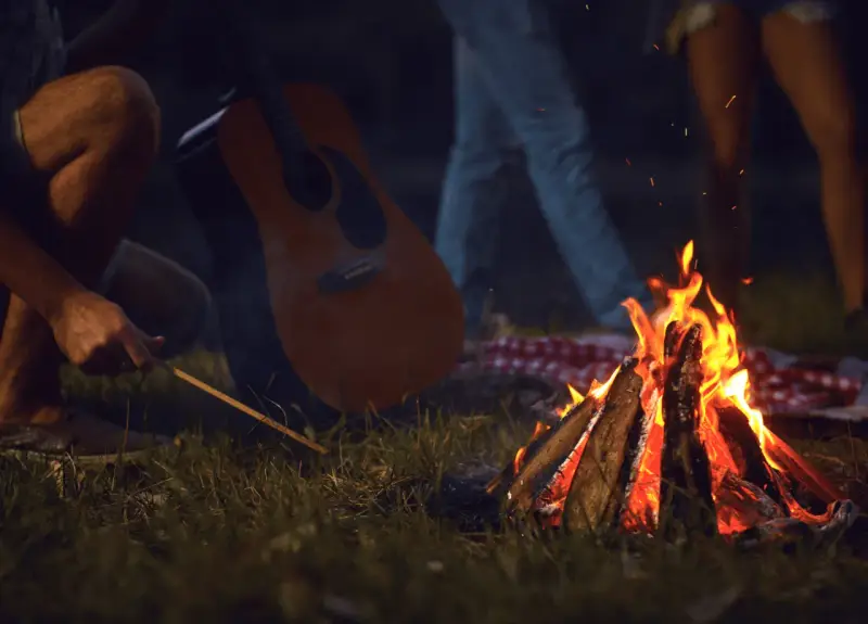 Przy ognisku, z gitarą w tle, rozbrzmiewają piosenki turystyczne i harcerskie.
