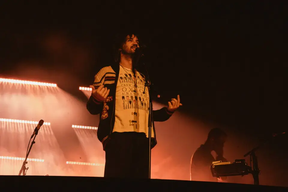 Kevin Parker z Tame Impala na koncercie w Gliwicach, w otoczeniu pomarańczowych świateł scenicznych.